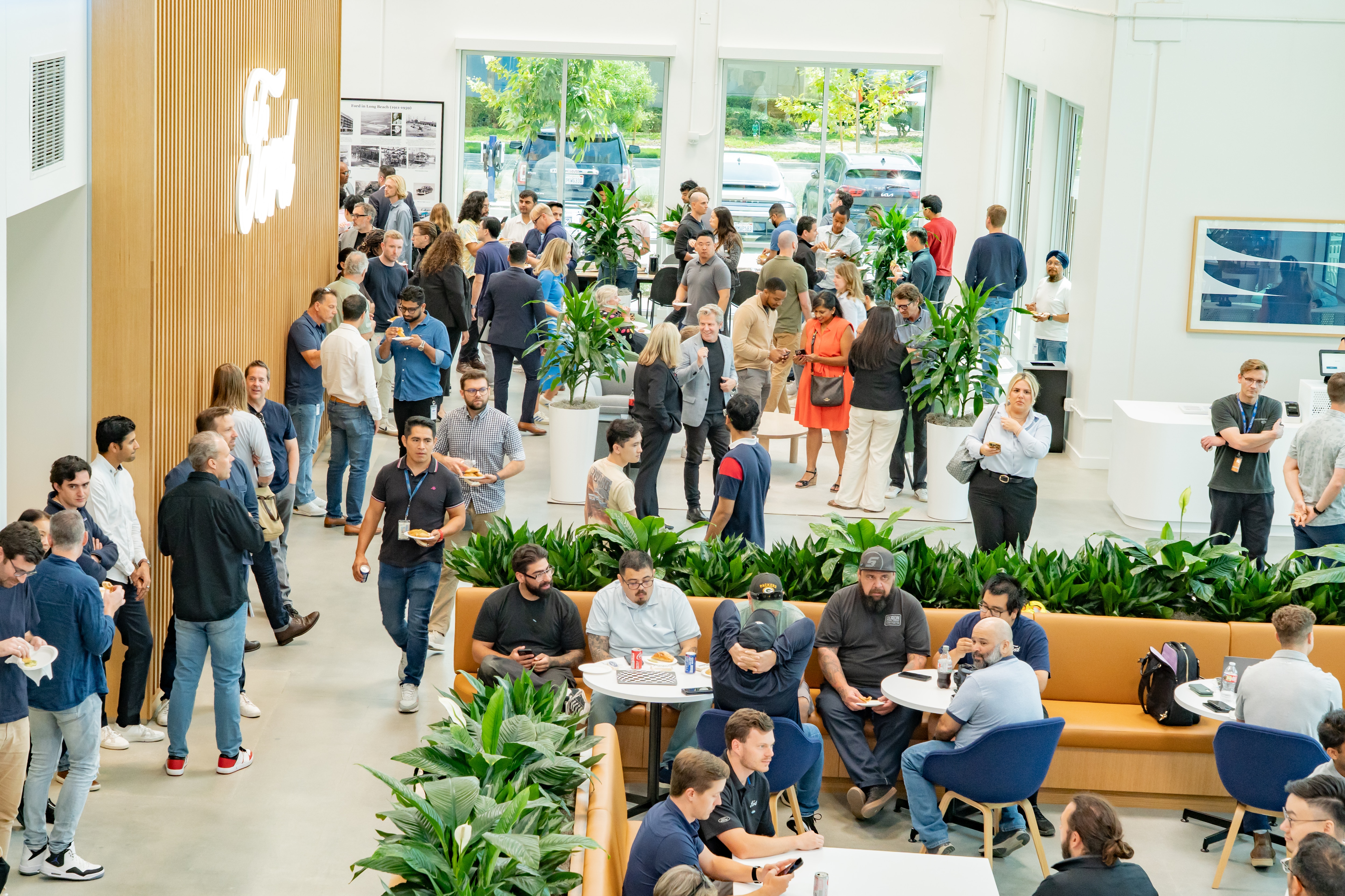 People gather in a brightly lit office space with lots of greenery and natural tones
